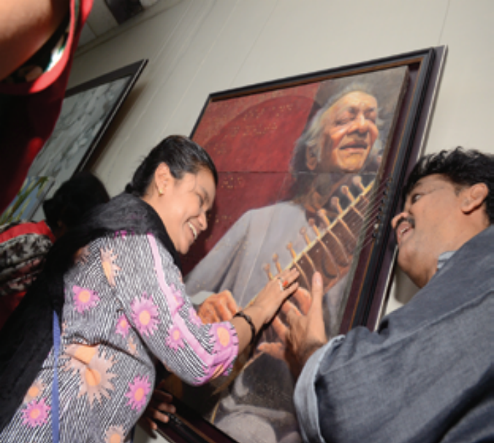 A visually impaired lady feeling the strings of sitar maestroRavi Shankar`s portrait by Hasabnis
